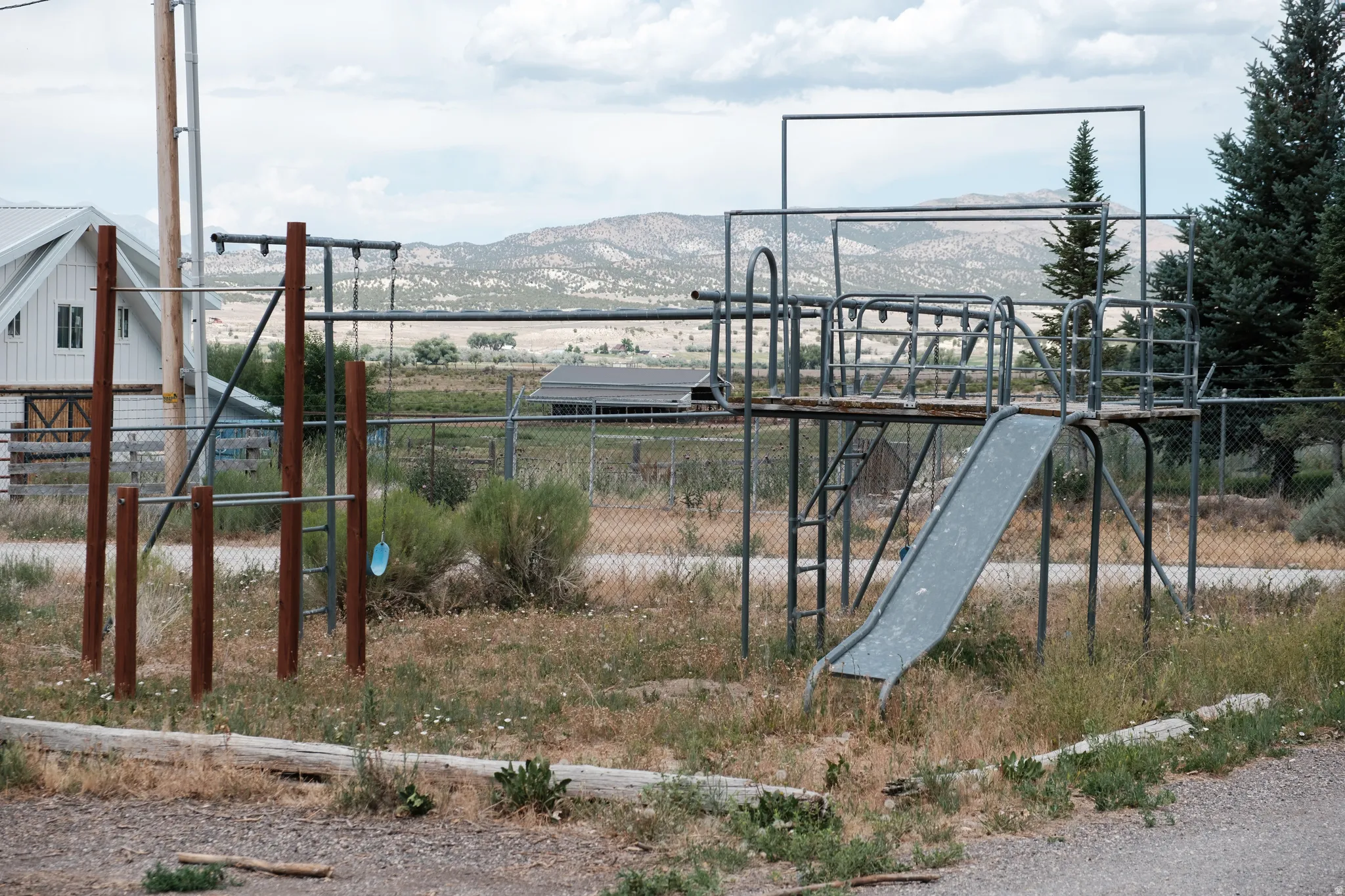 Outdoor recreational equipment featuring a metal slide, climbing bars, and a multi-level platform