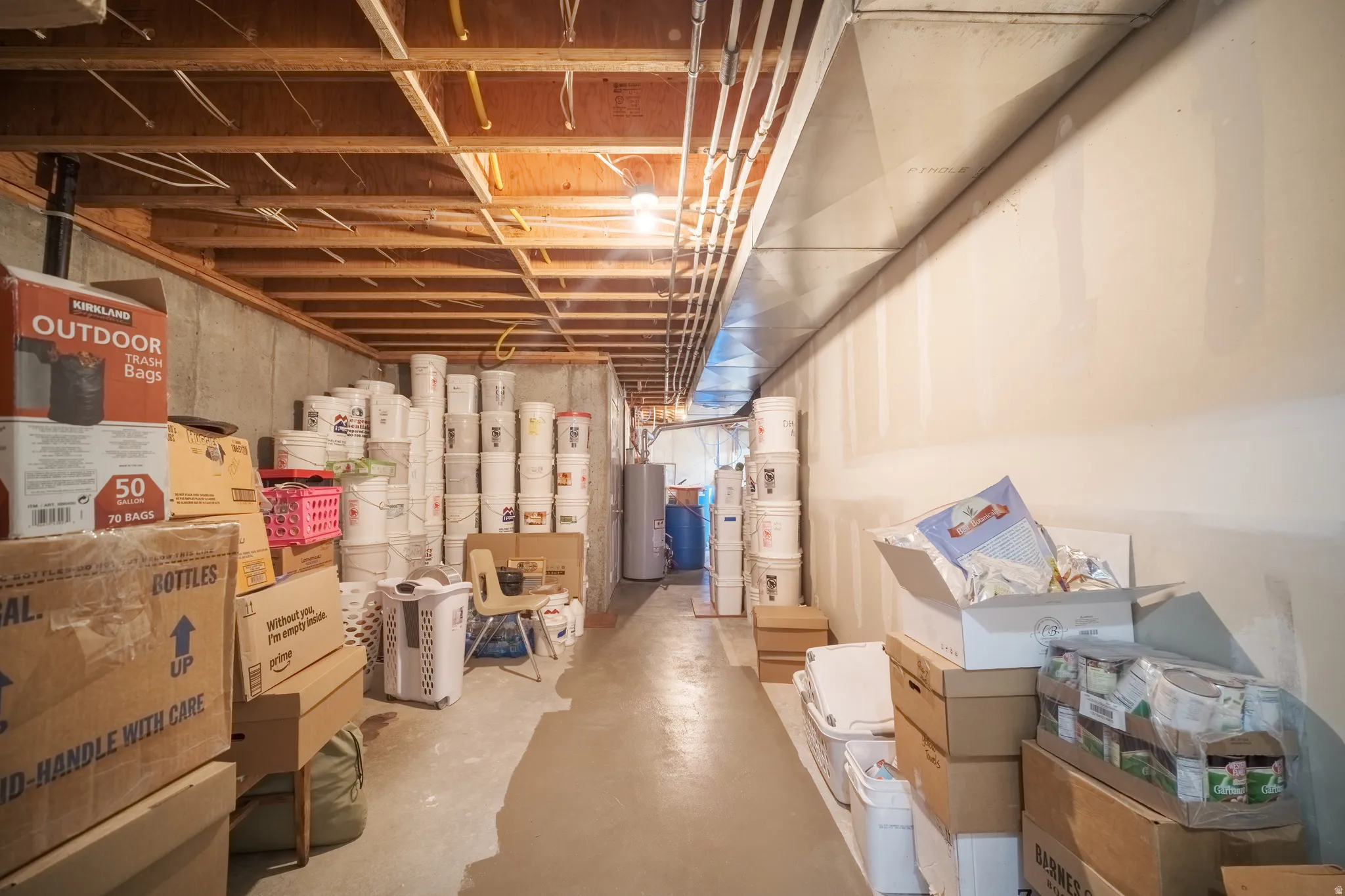 Unfinished basement featuring exposed wood joists, concrete foundation walls, and a concrete floor