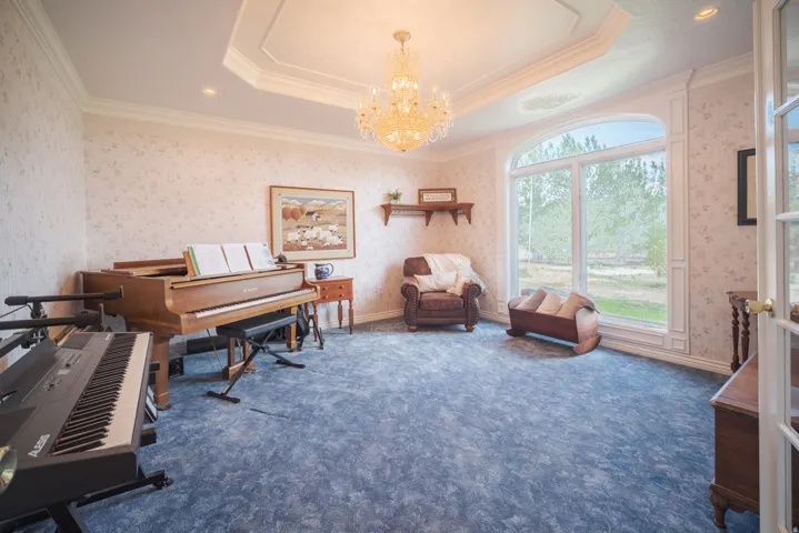 Spacious interior room featuring a large arched window, blue patterned carpet, and a decorative chandelier