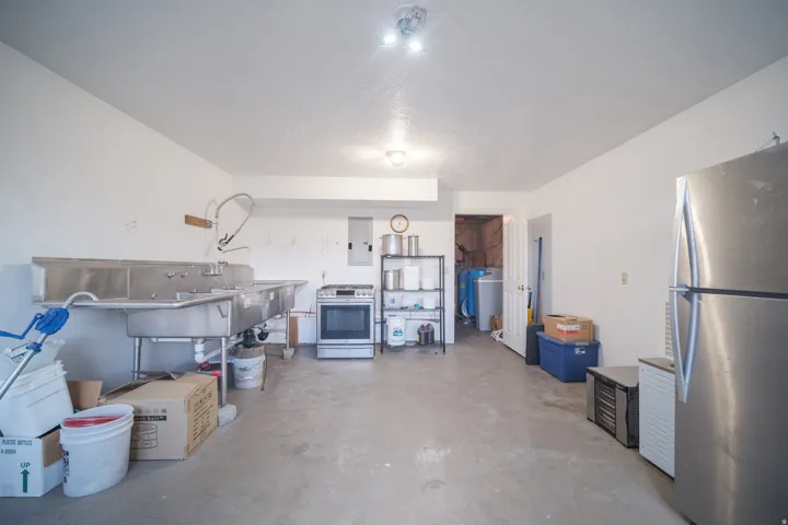 Utility space featuring a three-compartment stainless steel sink, a standalone oven, and a polished concrete floor