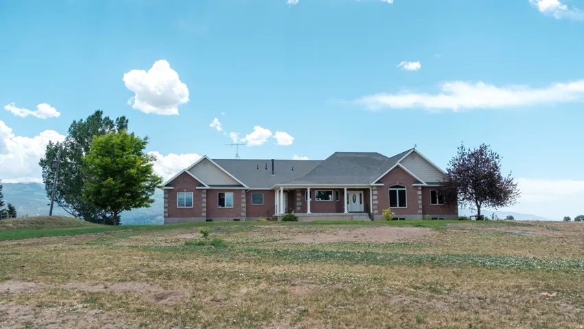 Ranch-style exterior featuring brick facade, gabled rooflines, and a covered front porch with white columns