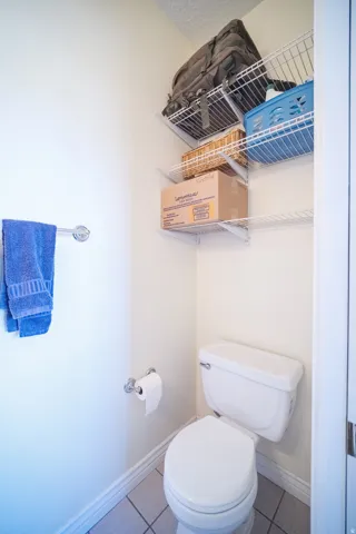 White toilet with a matching lid and tank, set on light tile flooring
