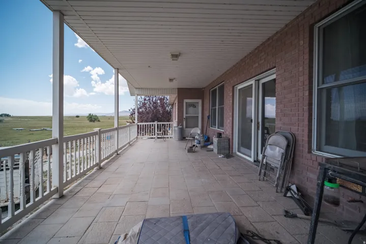 Expansive covered patio featuring brick exterior, white railing, and tiled flooring
