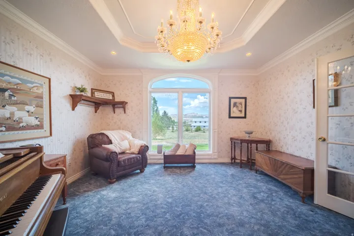 Room featuring an arched window, decorative crown molding, a central chandelier, patterned wallpaper, and recessed lighting