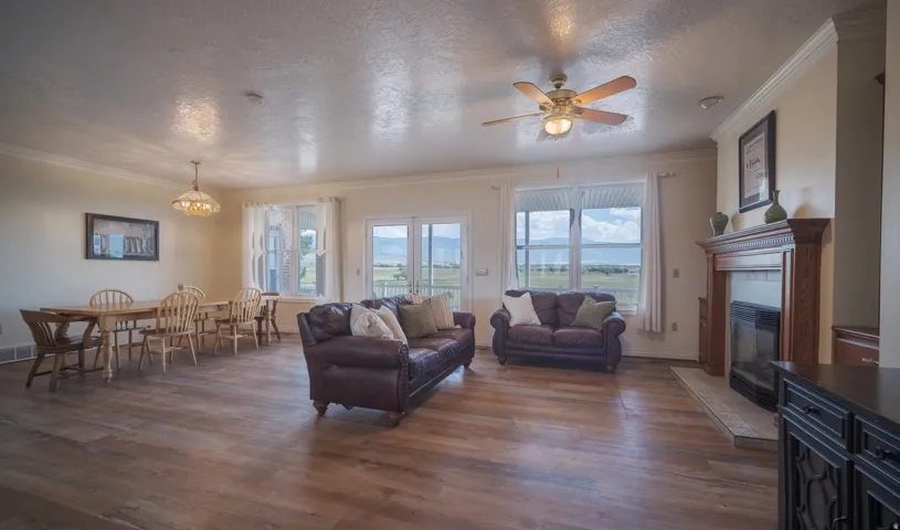 Spacious living area featuring wood-finish flooring, crown molding, and a built-in fireplace with a wood mantel