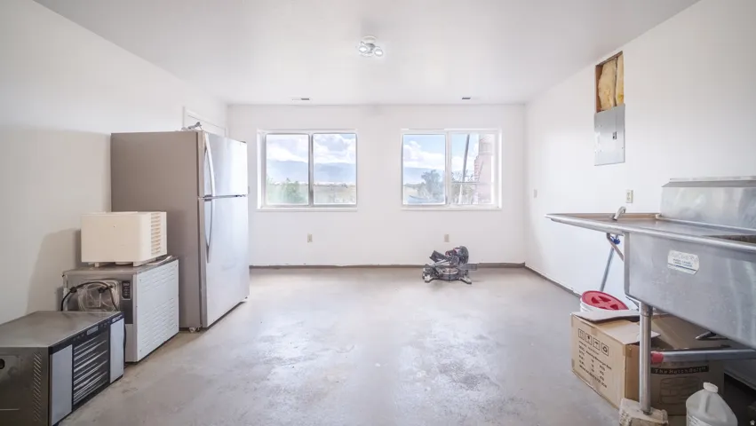 Spacious utility room featuring two large windows, a stainless steel commercial sink, and a durable concrete floor