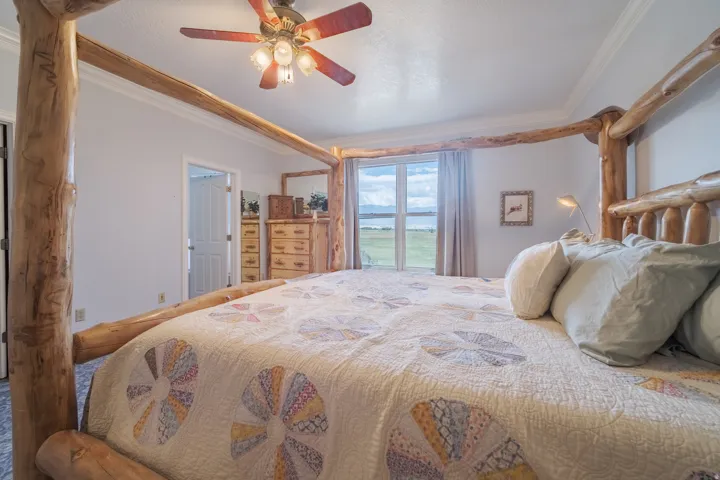 Spacious room featuring light gray walls, crown molding, a window overlooking a landscape, and a ceiling fan with integrated lighting