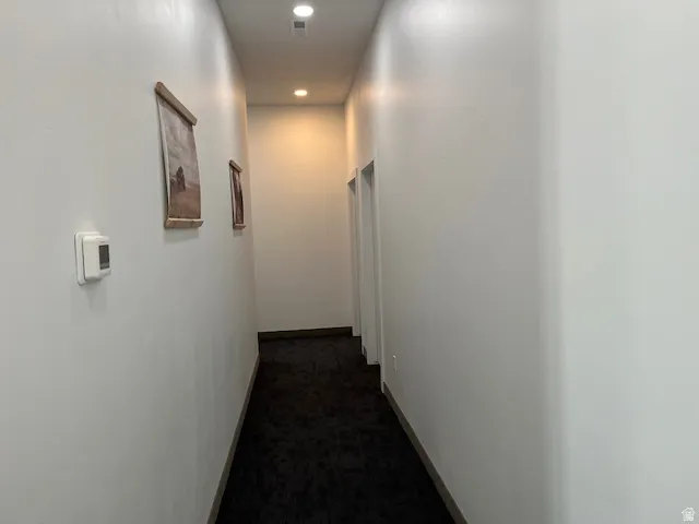 Corridor featuring recessed lighting and dark colored carpet