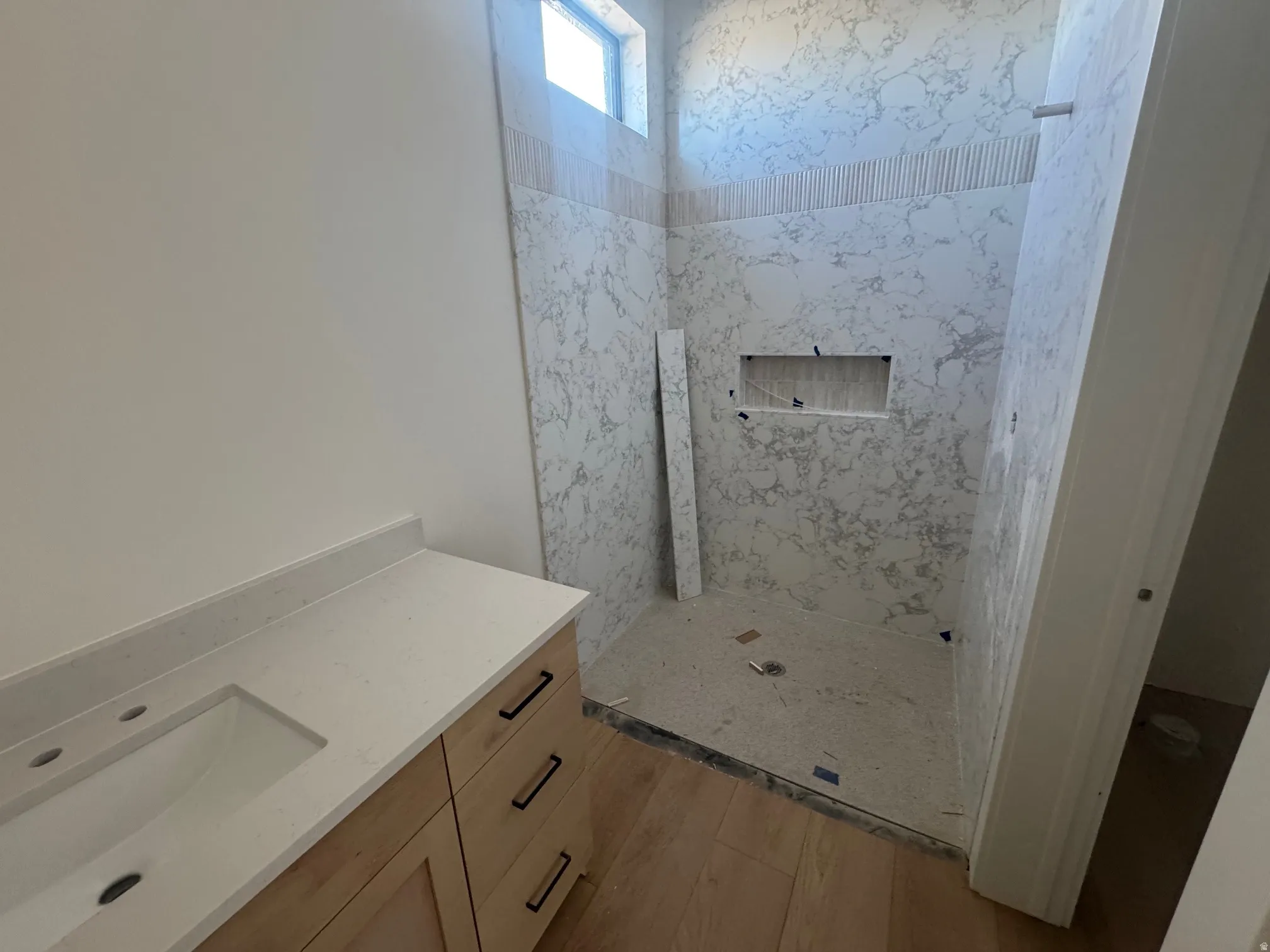 Full bathroom featuring vanity, a marble finish shower, and light wood-type flooring
