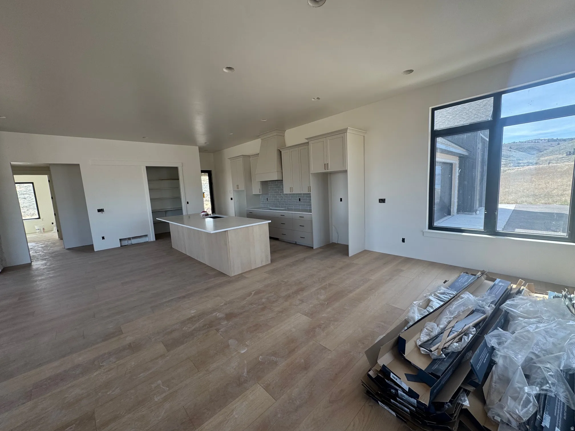 Kitchen with a center island with sink, open floor plan, wood finished floors, tasteful backsplash, and light countertops