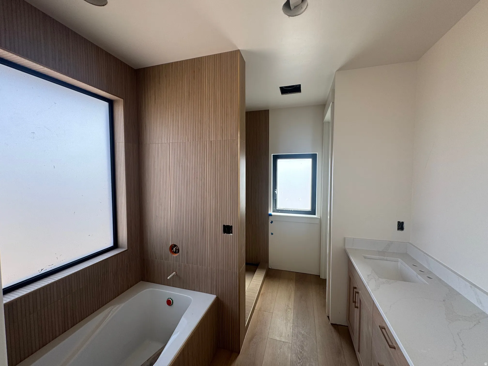 Full bath with vanity, a bath, and light wood finished floors