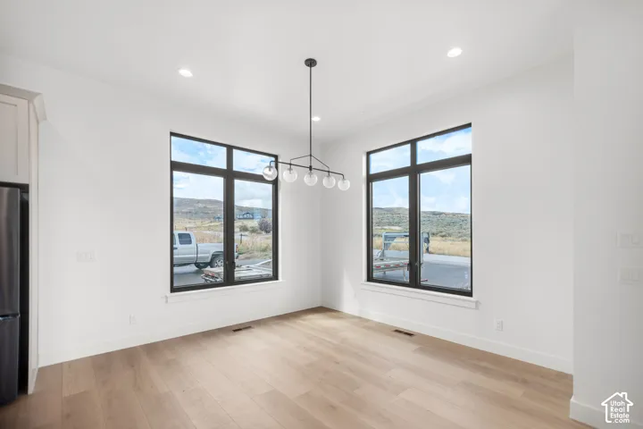 Light wood-finish flooring, recessed lighting, and a contemporary chandelier