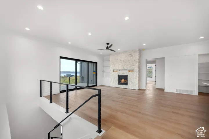 Spacious interior featuring wood-finish flooring, a stone-clad fireplace, and recessed lighting