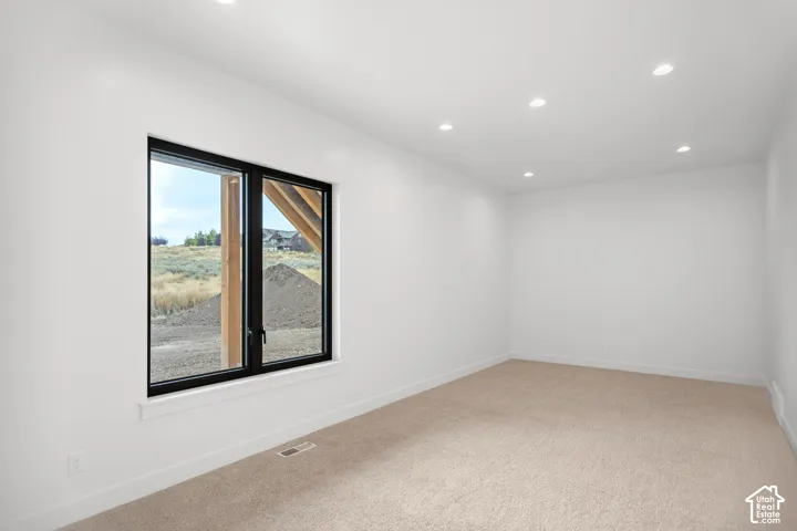 Recessed ceiling lighting, white walls, black-framed window, and neutral-toned carpeting