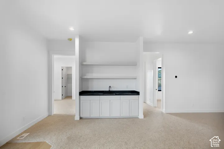 Built-in wet bar with white cabinetry, dark countertop, and integrated sink