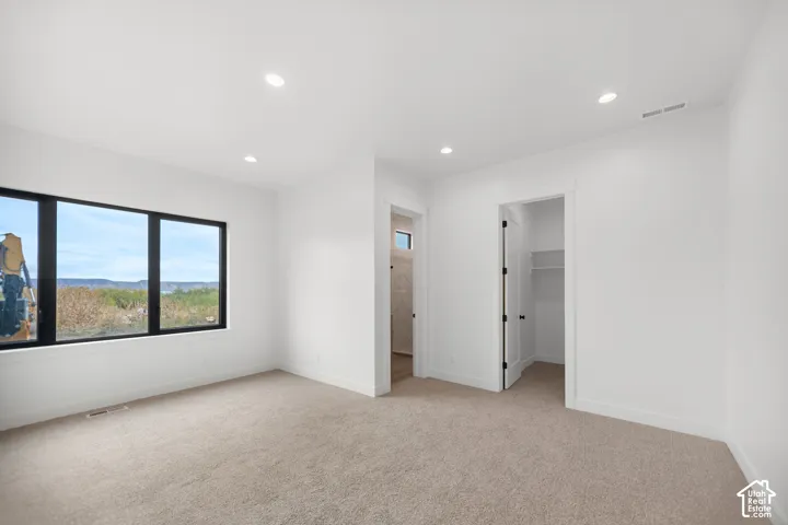 Recessed lighting, light-toned carpeting, ample natural light, and a built-in closet with shelving