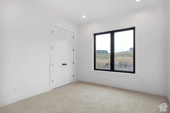 Recessed lighting, carpeted flooring, and a large window with black trim