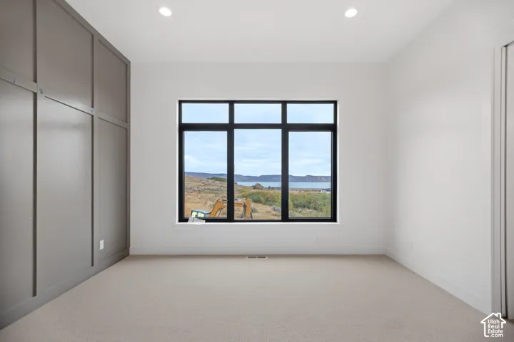 Recessed lighting, large multi-pane window, carpeted flooring, and a feature wall with decorative paneling