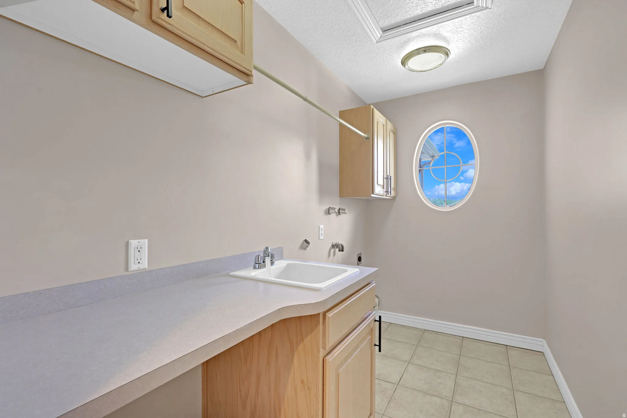 Laundry area with a textured ceiling, electric dryer hookup, cabinet space, light tile patterned floors, and hookup for a washing machine