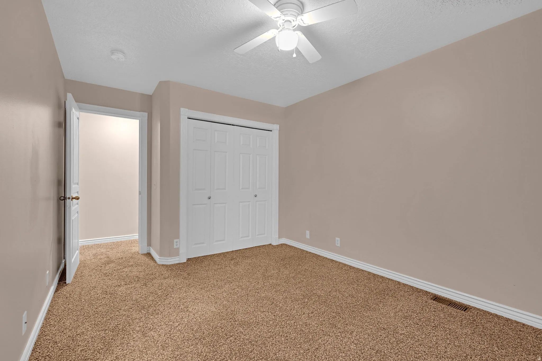 Unfurnished bedroom featuring light colored carpet, a textured ceiling, a closet, and ceiling fan