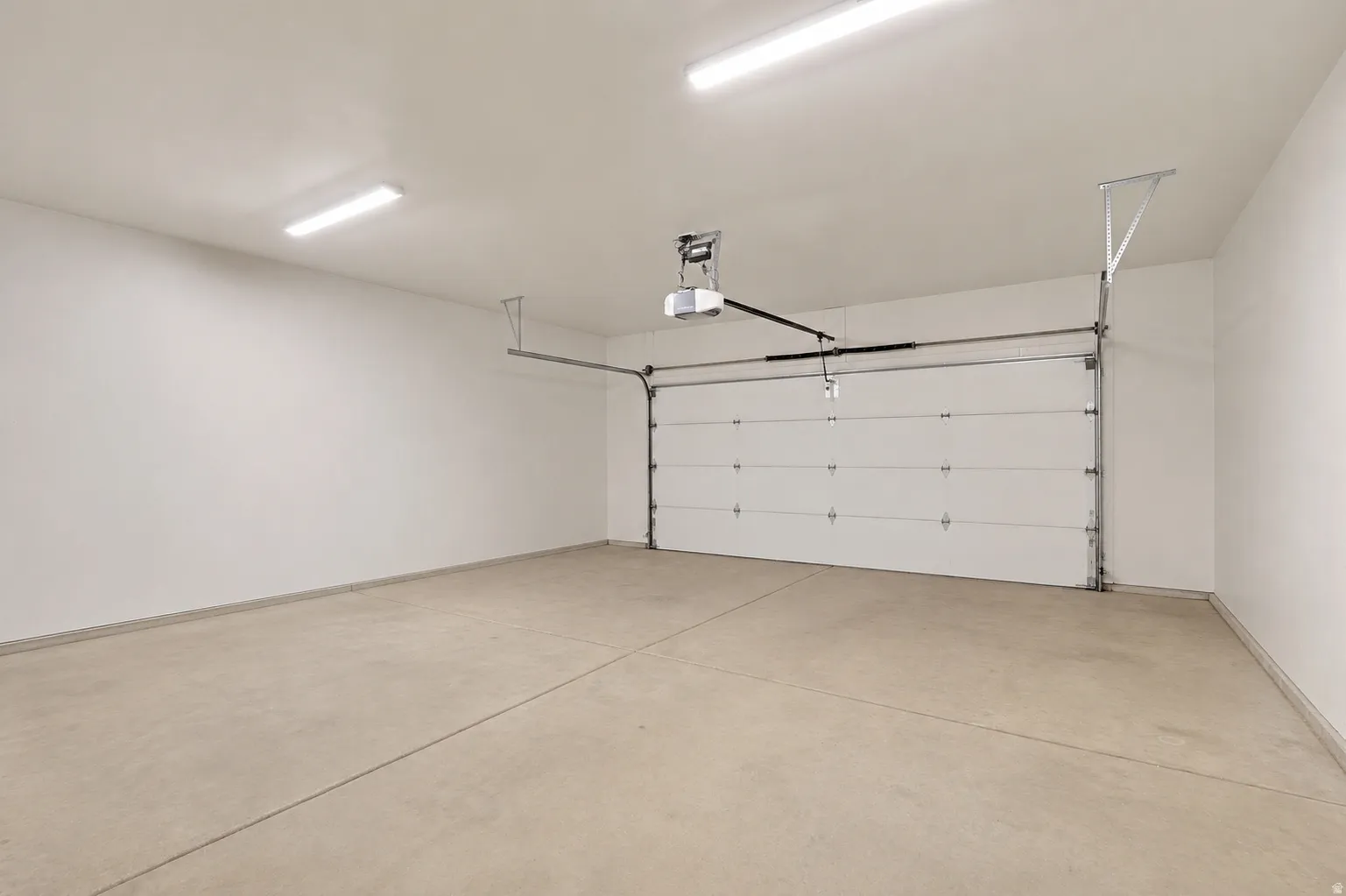 Spacious garage featuring a concrete floor, white walls, and bright overhead lighting