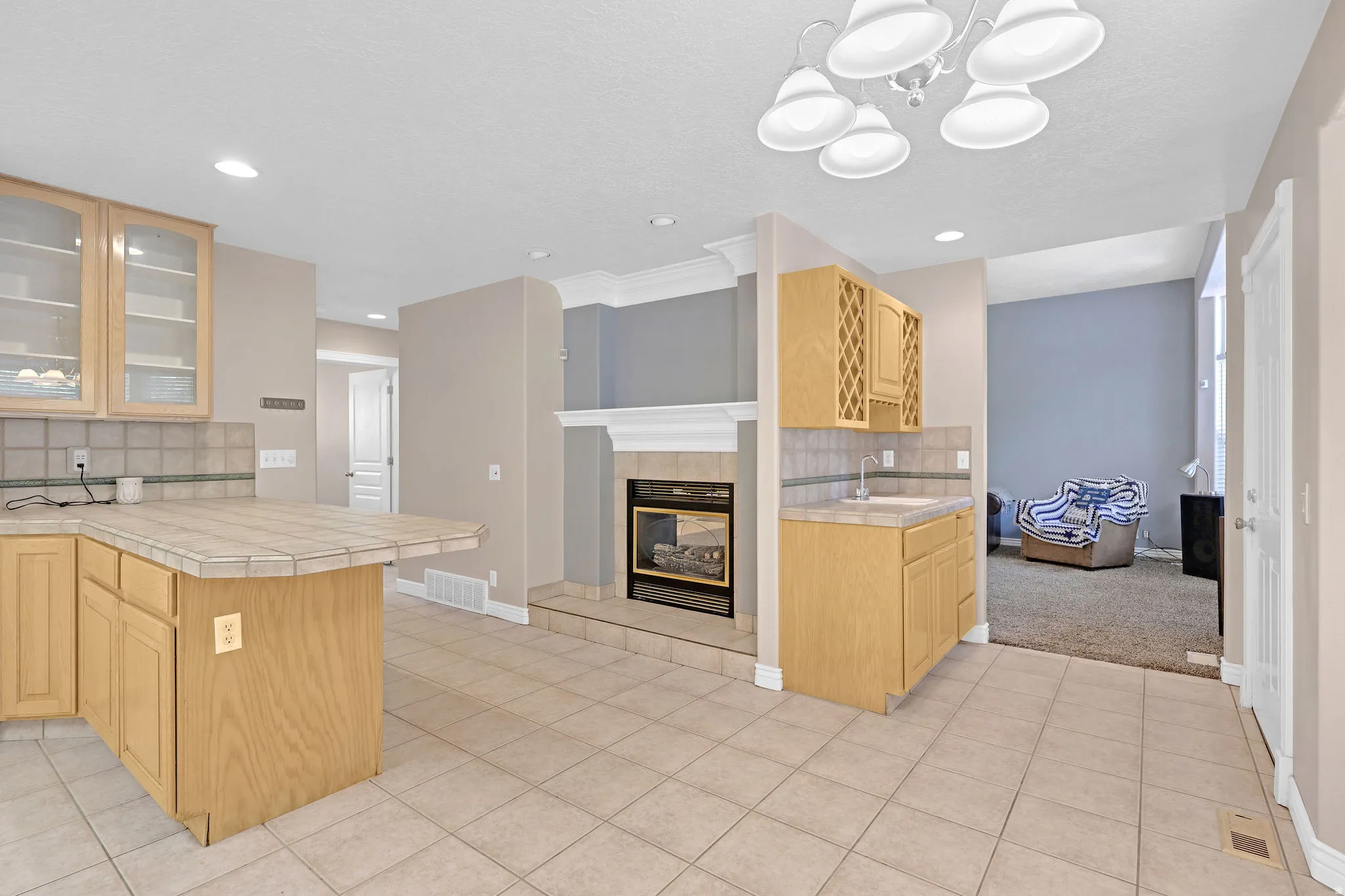 Kitchen with backsplash, glass insert cabinets, a peninsula, light tile patterned floors, and recessed lighting