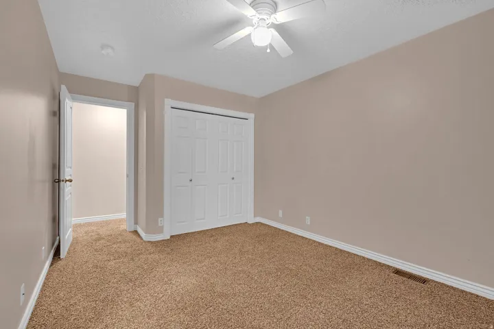 Unfurnished bedroom featuring light colored carpet, a textured ceiling, a closet, and ceiling fan