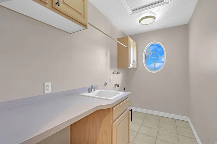 Laundry area with a textured ceiling, electric dryer hookup, cabinet space, light tile patterned floors, and hookup for a washing machine