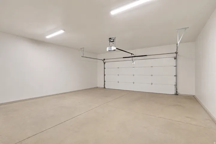 Spacious garage featuring a concrete floor, white walls, and bright overhead lighting
