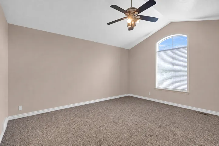 Interior room featuring a vaulted ceiling and a large arched window with blinds