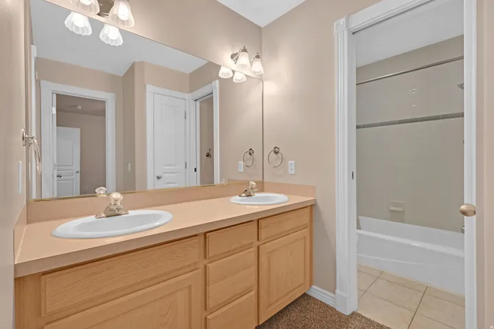 Full bathroom featuring light tile patterned floors, double vanity, and tub / shower combination
