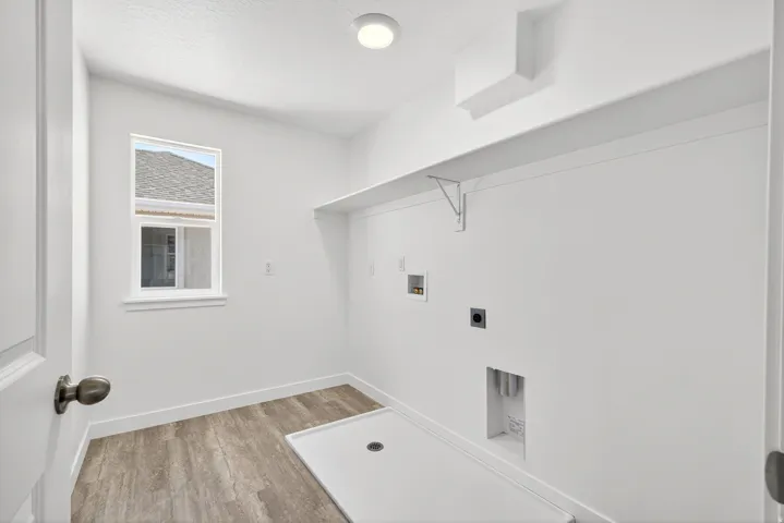 Laundry room featuring hookup for a washing machine, light wood-type flooring, electric dryer hookup, and a textured ceiling
