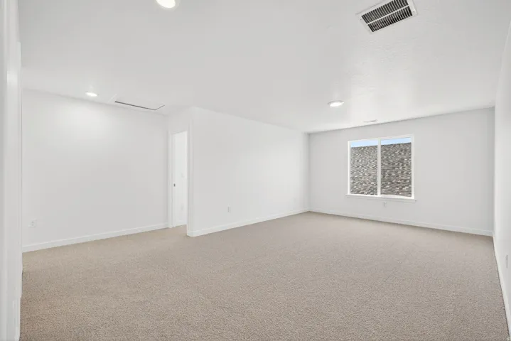 Unfurnished room with light carpet, attic access, and recessed lighting