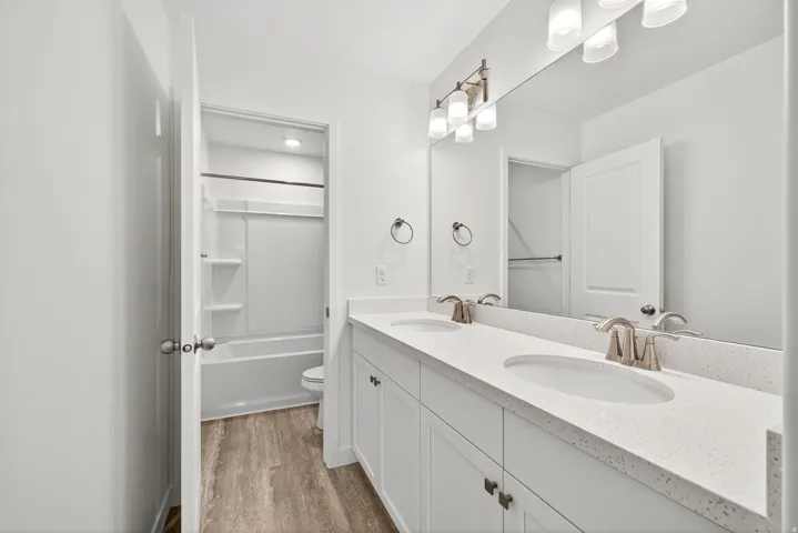 Full bathroom with double vanity, bathtub / shower combination, and light wood-type flooring