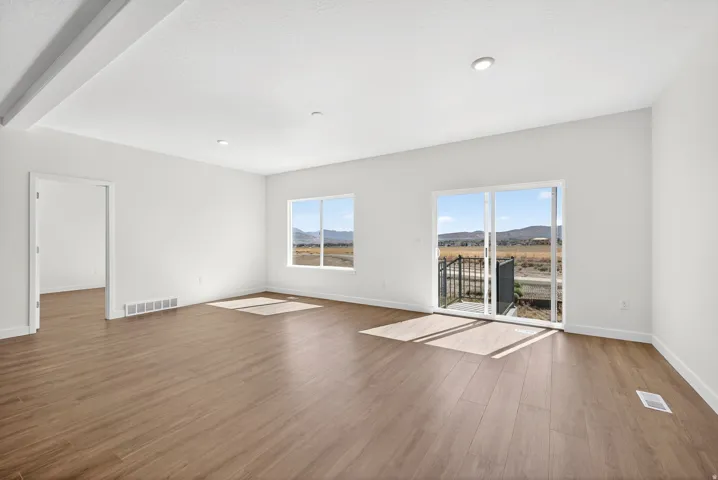 Unfurnished living room with light wood-style floors, a mountain view, recessed lighting, and beam ceiling