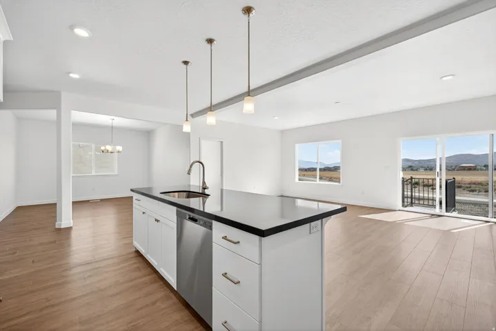 Kitchen featuring open floor plan, dark countertops, white cabinets, light wood-type flooring, and pendant lighting