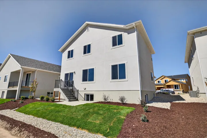 Back of property with a lawn, stairs, and stucco siding