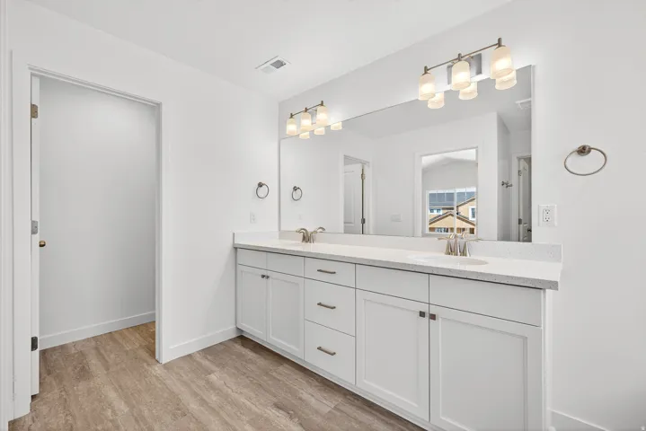 Bathroom with double vanity and light wood finished floors