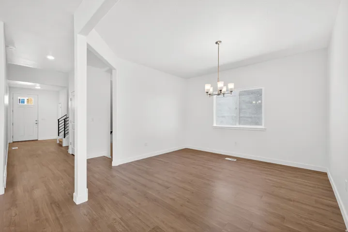 Unfurnished dining area with wood finished floors, a chandelier, and stairs