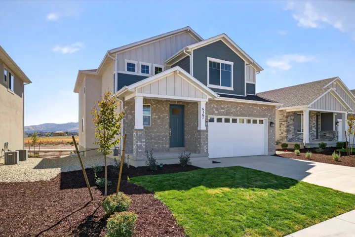 Craftsman-style home featuring board and batten siding, covered porch, driveway, and a front yard