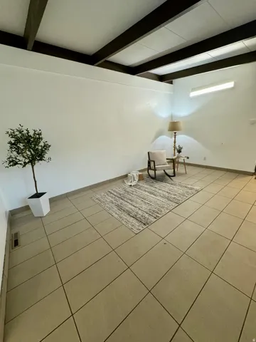 Unfurnished room featuring light tile patterned floors and beamed ceiling