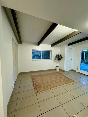 Unfurnished living room with beamed ceiling and tile patterned flooring
