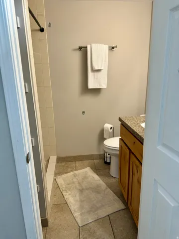 Full bath with tiled shower, vanity, and light tile patterned floors
