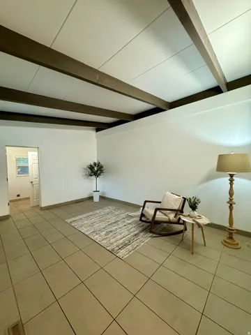 Unfurnished room with tile patterned floors and beamed ceiling