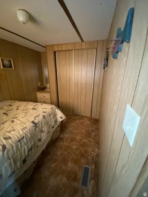 Bedroom with wood walls and dark colored carpet