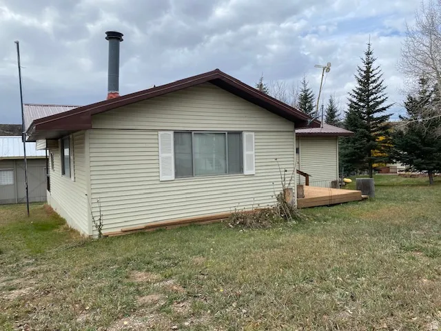 Rear view of house with a lawn, a metal roof, and a deck