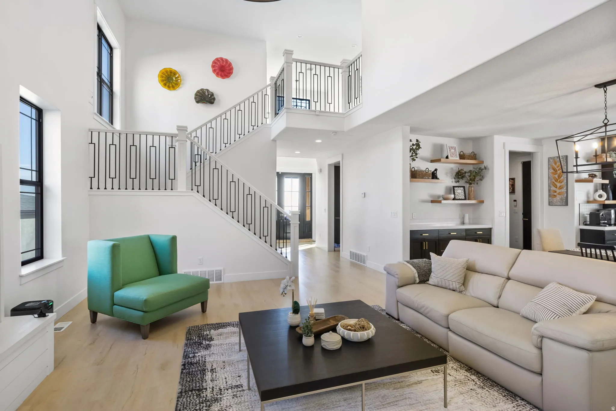 Living area featuring light wood-type flooring, stairs, a high ceiling, and a chandelier