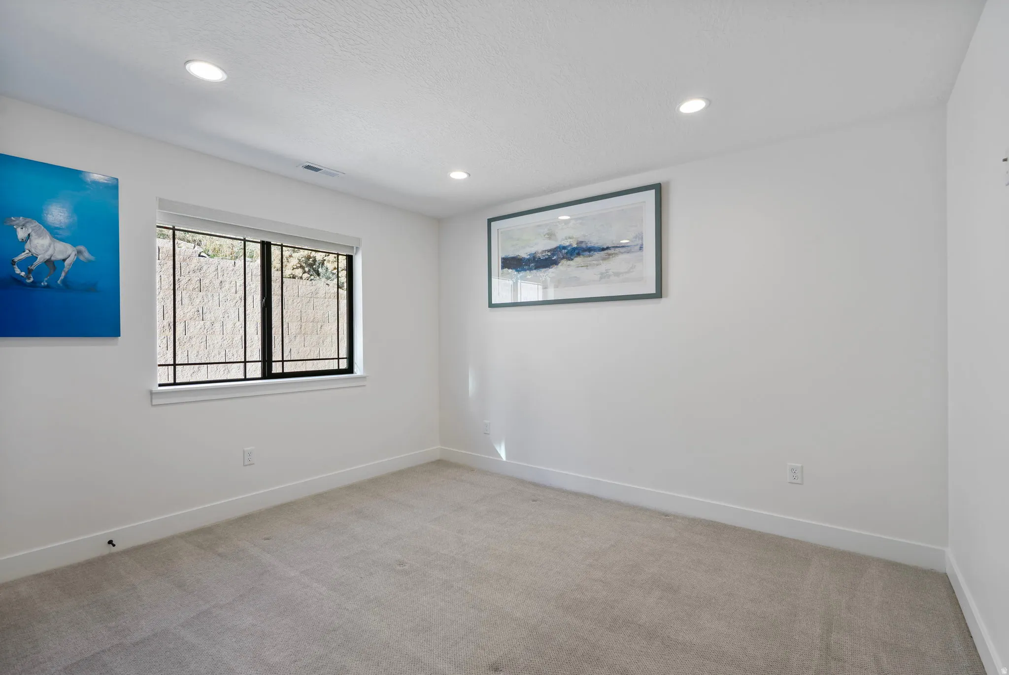 Empty room with light carpet and recessed lighting
