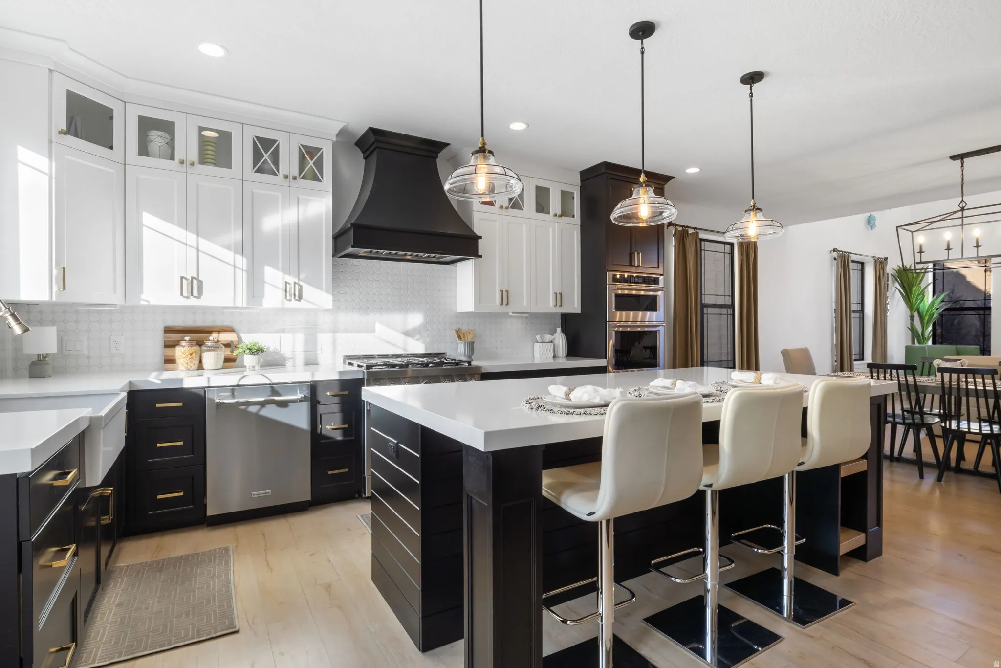 Kitchen featuring dark cabinets, a breakfast bar area, hanging light fixtures, glass insert cabinets, and premium range hood