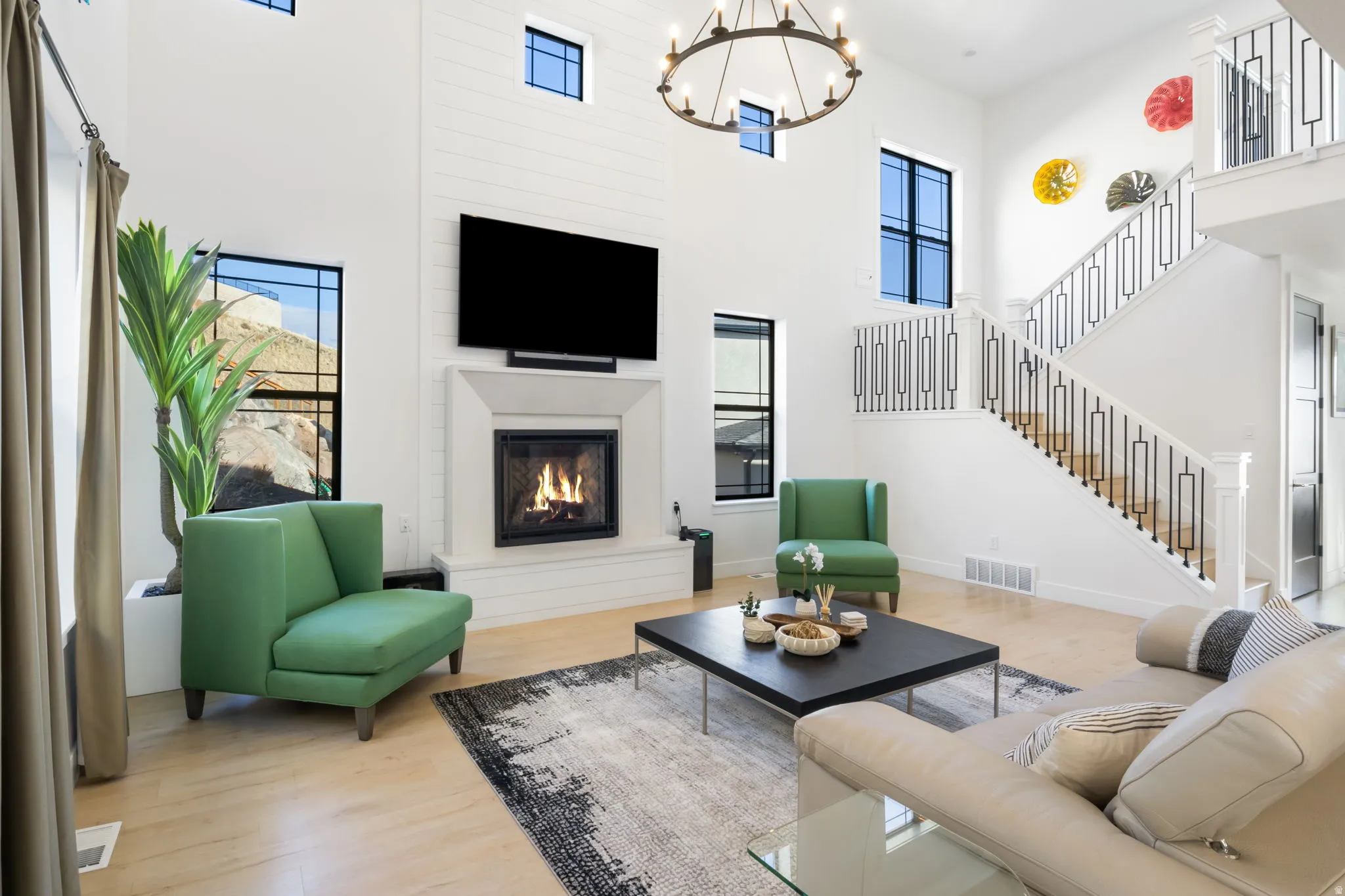 Living area featuring wood finished floors, stairs, a glass covered fireplace, a high ceiling, and a chandelier